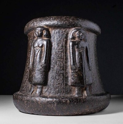 Rare Egyptian carved black stone ritual mortar, Middle Kingdom, circa 2055-1790 BC. Exterior shows standing figures, probably priests, in high relief, one wearing a long skirt, the other naked and wearing a long wig alternating to vertical lines of hieroglyphic inscription. Size: 240mm x 210mm (9.4in x 8.3in); Weight: 18.29kg (40lbs 5oz) Opening bid: £8,000/$10,195