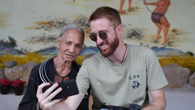 Italian vlogger Fabio Nodari takes a selfie with a Li elder in Hainan's Binglanggu (Betel Nut Valley) Li and Miao Cultural Tourism Area. (PRNewsfoto/Hainan International Media Center (HIMC))