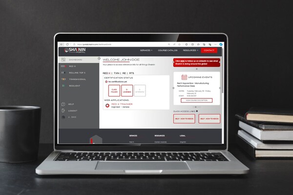 Laptop displaying the Shainin Portal dashboard with navigation menu, certification status, and quick access links on screen.