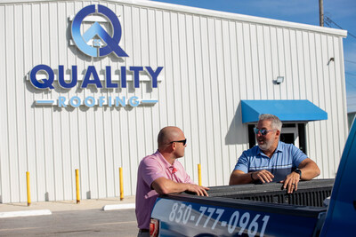 Two dedicated team members of Quality Roofing Solutions engage in a focused discussion outside their Pensacola headquarters. The building, located at 110 W Herman Ave, serves as the operational hub for the company's extensive services across Northwest and Central Florida.