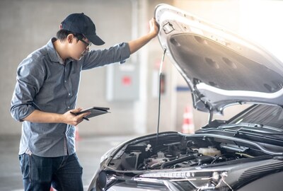 Technician checking the under the hood of a car