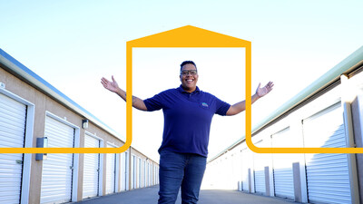 A smiling woman standing with her arms outstretched between two rows of storage units. A yellow graphic in the shape of a garage frames her.