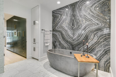 The primary bath includes a handsome soaking tub in stone. A wall of onyx provides an elegant backdrop. TexasLuxuryAuction.com.