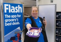 A photo of a Real Canadian Superstore colleague holding food in her hand while standing in front of the Flashfood fridge. (CNW Group/Loblaw Companies Limited - Public Relations)