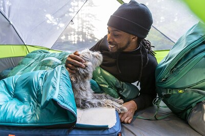 Timberdog model Brandon Davis-Loper camps with Timberdog mascot, Kashi, cozied up in her RuffRest Ultimate Dog Bed