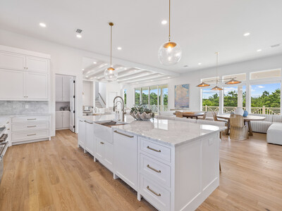 Interiors at 100 Brenda Lane are in the “beach house chic” style, and feature bright and spacious living areas filled with natural light. The gourmet kitchen and cozy living room are shown here. 30ALuxuryAuction.com.