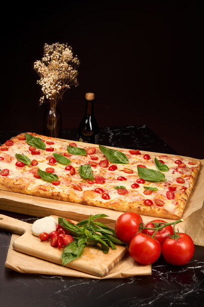 Angelina Bakery’s pinsa topped with cherry tomatoes, fresh basil, and mozzarella, capturing the bright flavors of a traditional Italian garden.