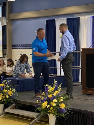 Al Fagundes presents Caleb Norris with a scholarship, demonstrating A. Fagundes Plumbing & Heating Inc.  commitment to supporting the next generation of skilled trades professionals.