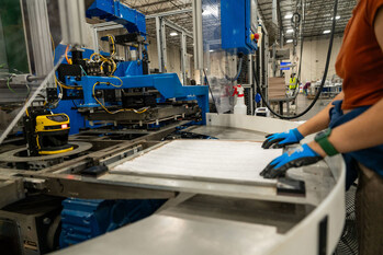 An associate works alongside automated equipment designed to streamline the assembly process.