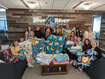 Blue River PetCare colleagues pose with the blankets they made for Live Like Roo, a charity that supports pets diagnosed with cancer.