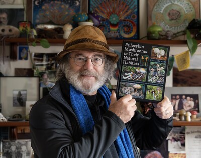 Paul Stamets holding his new book, Psilocybin Mushrooms in Their Natural Habitats