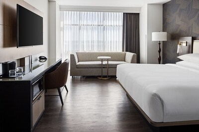 A renovated king guest room at Bloomington-Normal Marriott Hotel & Conference Center, showcasing sleek furnishings, warm textures, and natural light for a restful, modern stay.