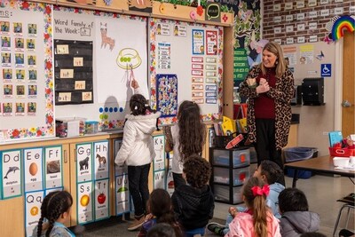 Elementary students interact at the whiteboard during an activity, while the teacher observes and encourages participation, capturing Imagine IM’s commitment to inclusive, student-centered instruction.
