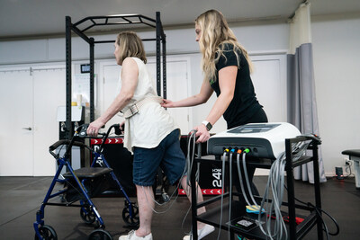 A physical therapist works one-on-one with a Bootcamp participant, using the Neubie to support walking practice and build strength.