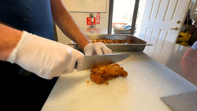 A community partner prepares donated chicken filets to be incorporated into a meal for those facing food insecurity.