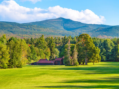 Property grounds include a vast expanse of manicured lawns. The main house and guest cabin are shown here, in the distance, with Whiteface Mountain in the background. NewYorkLuxuryAuction.com.