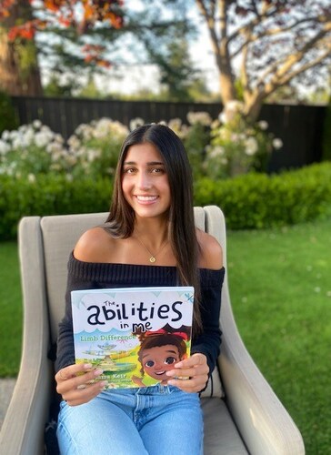 Olivia Metz holding a copy of The Abilities in Me: Limb Difference