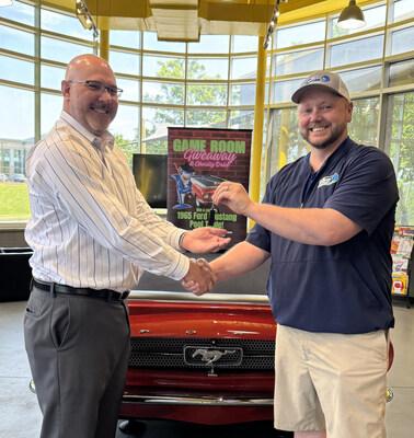 Pool table winner, Jonathan Simms, receives the custom Ford Mustang pool table from RipTide Car Wash General Manager, Joshua Siler.
