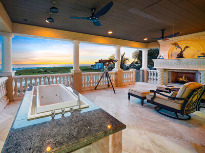 The home features two spacious, oceanfront terraces, each with a stone fireplace. The upper terrace (pictured here, located off the primary bedroom suite) also includes a vanishing-edge Jacuzzi tub with rainfall shower heads – perfect for an evening soak while enjoying the property’s direct views of Florida’s sunsets. OceanfrontLuxuryAuction.com.