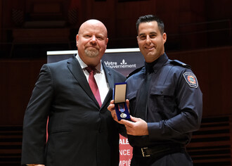 Le pompier Michael Therrien, du Service de s&#233;curit&#233; incendie de Montr&#233;al, re&#231;oit la M&#233;daille pour acte m&#233;ritoire des mains du ministre de la S&#233;curit&#233; publique, ministre responsable des Relations avec les Premi&#232;res Nations et les Inuit et ministre responsable de la r&#233;gion du Nord-du-Qu&#233;bec, M. Ian Lafreni&#232;re. (Groupe CNW/Cabinet du ministre de la S&#233;curit&#233; publique)