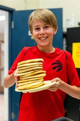 A young student beams while holding a stack of pancakes during a Make Happy Tummies school visit — a morning of good food, laughter, and community. (CNW Group/Stacked Pancake & Breakfast House) A young student beams while holding a stack of pancakes during a Make Happy Tummies school visit — a morning of good food, laughter, and community. (CNW Group/Stacked Pancake & Breakfast House)