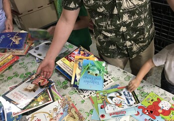 Parent and young child volunteering to sort books at literacy organization