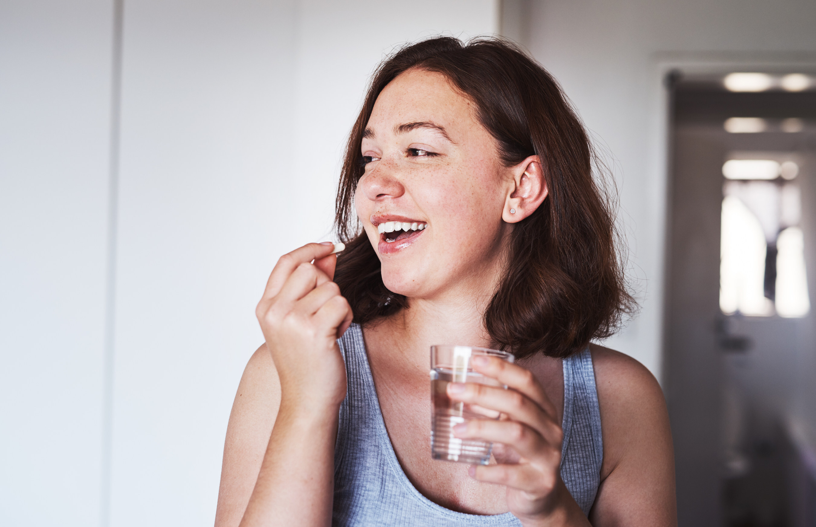 Young woman swallowing a small pill