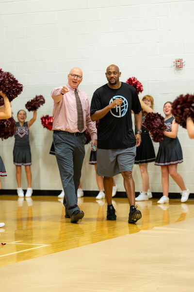 Clarksville Christian Director of Athletics Jason Shelton (left) ushers Clarksville Girls Basketball Coach Trenton Hassell (right) into the gym for a surprise celebration of his being named National Coach of the Year by the National Christian School Association in early October.