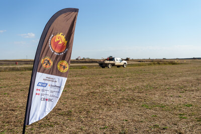 A feather flag for Wicehtowak Solar Ltd., mentioning the partnership with the CIB and other organizations, stands in the foreground of a dry, open field with a white pickup truck and construction equipment visible in the distance under a clear blue sky. (CNW Group/Canada Infrastructure Bank) A feather flag for Wicehtowak Solar Ltd., mentioning the partnership with the CIB and other organizations, stands in the foreground of a dry, open field with a white pickup truck and construction equipment visible in the distance under a clear blue sky. (CNW Group/Canada Infrastructure Bank)