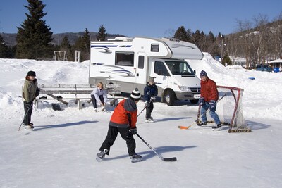 Kids and adults play ice hockey outside RV in snowy conditions. Kids and adults play ice hockey outside RV in snowy conditions.