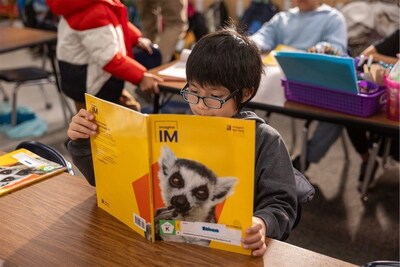 A young elementary student reads an Imagine IM K–8 math book, reflecting focused classroom engagement with Imagine Learning’s print resources.