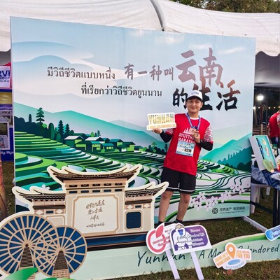 A runner takes a photo at Yunnan's tourism promotion booth during the Ayutthaya Marathon 2025, which was held Sunday in Thailand's ancient city. [Photo by Li Yingqing/chinadaily.com.cn] (PRNewsfoto/chinadailyhk.com)