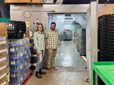 Emily James and Ryan Rasmussen with the Oshkosh Area Community Pantry stand at the entrance of their Barr, Inc. walk-in freezer installed through the Coolers for a Cause initiative.