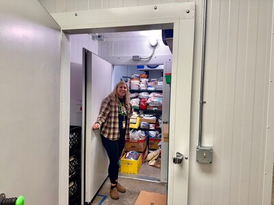 At Day by Day Shelter, Yolanda Suess demonstrates the Barr, Inc. combo cooler/freezer that expands the shelter’s capacity to safely store both refrigerated and frozen foods through Coolers for a Cause.