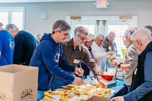 ACECO employees in an assembly line packaging food for Helping Harvest