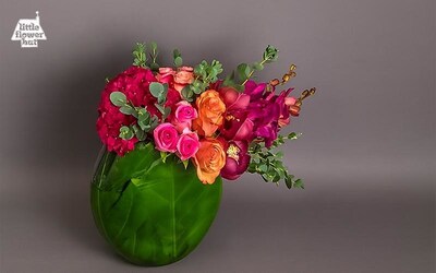 Vibrant floral arrangement in a glass vase wrapped with green leaves, featuring roses, hydrangeas, and orchids. Vibrant floral arrangement in a glass vase wrapped with green leaves, featuring roses, hydrangeas, and orchids.