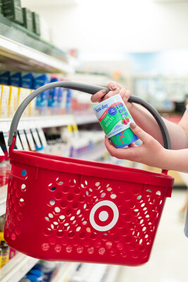 A Target shopping basket being held by a woman holding a bottle of first day vitamins