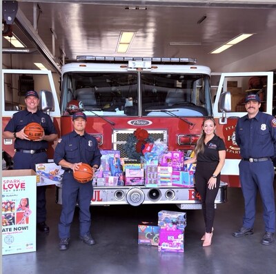 Group photo inside the Fullerton Fire Department showing Rooter Hero representative Alexandria Lavoie standing with firefighters in front of a fire engine and a large display of donated toys, highlighting the Rooter Hero toy drive donation.