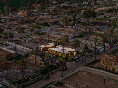 Aerial view of a residential neighborhood after a wildfire, with damaged homes surrounding a custom pre-engineered metal building (PEMB).