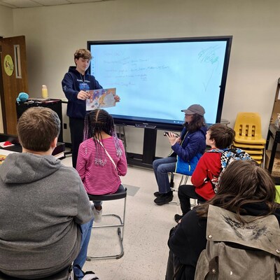 Connor Marek reading his book, Wired Differently to elementary students in efforts to inspire students to pursue hands-on STEM learning through FIRST® programs.