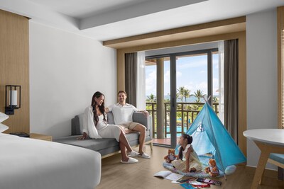 Phuket Marriott Resort & Spa, Merlin Beach - A family of three relaxes in a resort room with a view of the beach, featuring M Passport Family Package