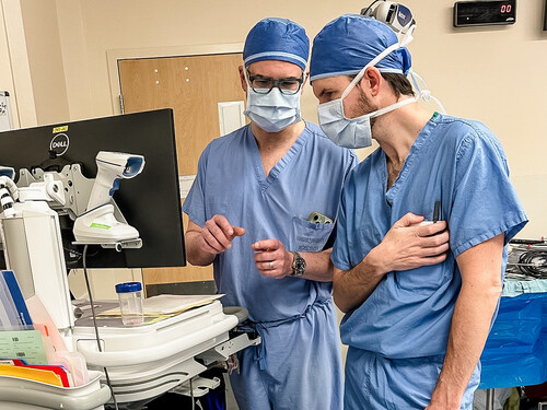 Dr. Langerman (left) and Zach Smith (right) review workflow systems at a pilot facility to ensure seamless integration into the existing OR environment. Dr. Langerman (left) and Zach Smith (right) review workflow systems at a pilot facility to ensure seamless integration into the existing OR environment.