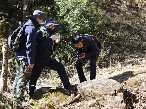 Pan Jiarong (second from left) examines a piece of mineral rock in Nujiang prefecture, Yunnan province, in January. [Photo by Li MenghanChina Daily]