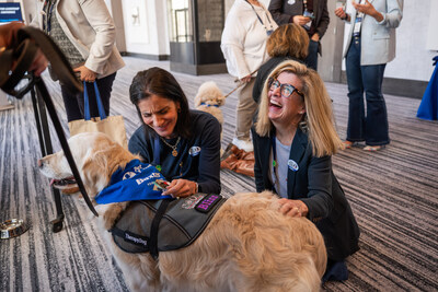 Two Baxter leaders petting and engaging with a Pet Partners therapy golden retriever