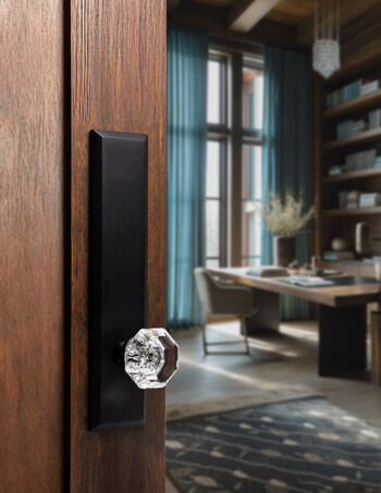 Ageless Iron™ matte black door hardware pairs a faceted crystal knob with a tall architectural plate, showcasing mixed-material design.