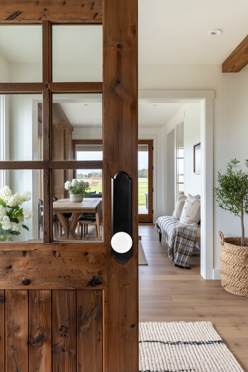 A crisp white porcelain knob on a tall matte black plate adds clean contrast to rustic wood, blending modern simplicity with warm, natural textures.