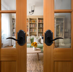 Sculptural matte black levers on arched plates bring bold contrast to warm wood doors, adding refined architectural character to modern interiors.