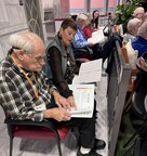 A volunteer helping a Local Come Together Choir participant follow along with the music