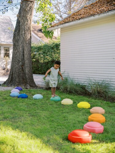 The image features a young child walking along Nuby's new stepping stone product: StepPebbles