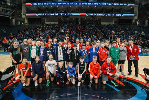 The 12-13-year-old Finalists pose with Regional Director volunteers and a crowd of their fans and family. The Getty Powell Award winners, who made the most regulation free throws of any other competitors, Logyn Parkinson and Duncan Walker, are near center wearing champion hats.